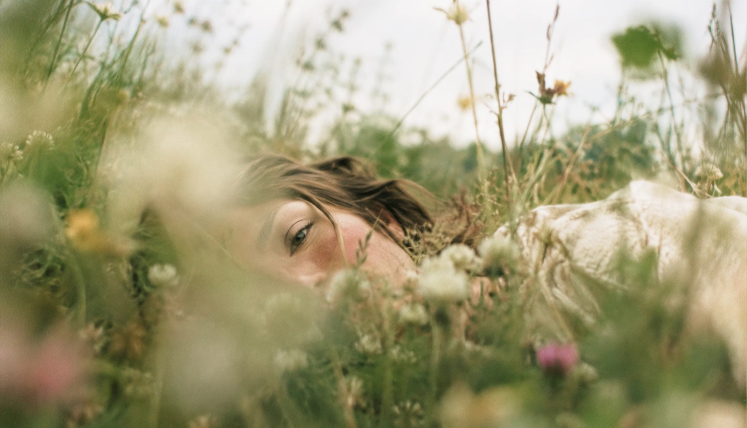 Vrouw die tussen wilde bloemen en grassen in een weide ligt